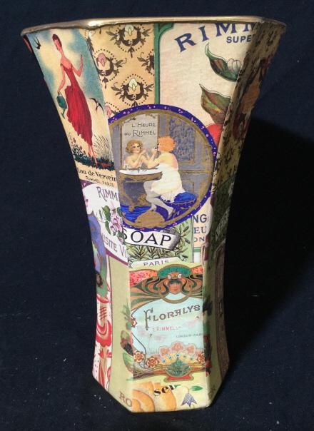 Vintage collage Decoupage tall glass flower vase: Vintage glass flower vase measuring approximately 10 inches tall. Hexagonal Shape. Collage features various drawings, patterns, and ads. Rim is painted gold. Black Felt bottom. Brand unknown. Vase, gl