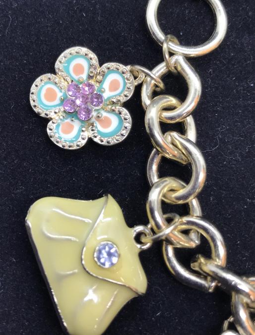 Toggle Clasp Enameled Charm Bracelet: Charm bracelet with a purse, flower, watch, blazer, shoe, cell phone & blue genie bottle charms. Gold tone chain link. Large toggle clasp. Charms hand app 1 in. or less. Adjustable position loop, 6.5 