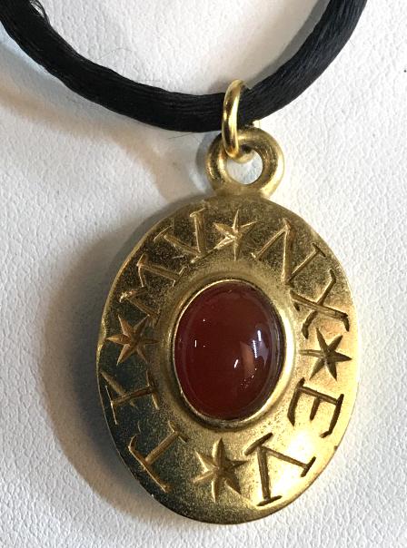 Signed Carolee Pendant Cord Necklace: Pendant has Carnelian Center cabochon, bezel Set in gold tone metal with inscribed letters ‘TI,MV,EX,MV’ . Back signed CAROLEE w/ copyright symbol. Cord 15 in, over the head, can be substituted fo