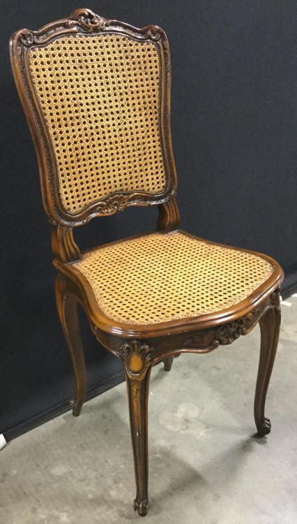 Intricately Carved Wooden Caned Side Chair: Side chair has intricately carved wooden detail. Piece has Caned Seat and backrest. Some carvings have ornate detail. piece Measures approx 39 inches tall 29 inches wide 20 inches deep. Piece appears