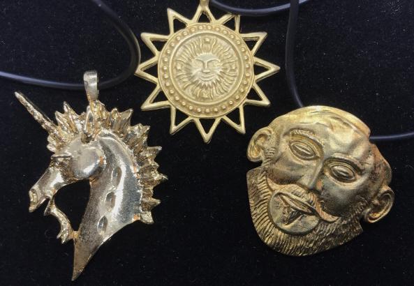 Lot 3 Gold Tone Figural Pendant Necklaces: Sun Medallion, Unicorn and Mask of Agamemnon pin/charm, all pendants in gold tone fashion metal in cords. Longest cord measures 18 in, other cords app 16 in. Unicorn pendant measures 2 x 1.25 in. Othe
