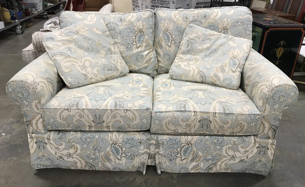 Upholstered Two Seat Sofa: Upholstered Two Seat Sofa In cream, blue, and brown toned Upholstered linen fabric with floral, scroll, and leaf design, marks cushions and to skirt of couch, measures approximately 66 inches long x 4