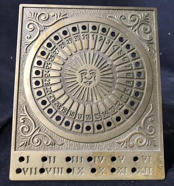 Gold Toned Brass Sun Calendar: Piece is gold toned & brass. Contains intricate detail. Piece has depiction of sun with face in center & is numbered to 31. Piece measures approx 5.5 inches tall 4.5 inches wide. astrological collecti