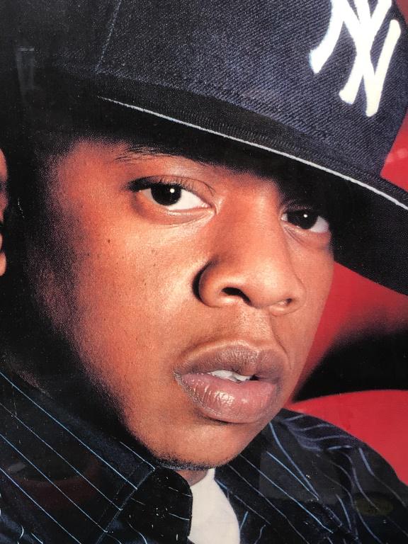 Framed Poster Print of Jay Z, American Rapper: Framed poster print of Jay Z’s portrait. Print is matted and set behind glass in silver tone composite frame. Measures approx 26 inches in height by 20 inches in width with frame. Print will need re