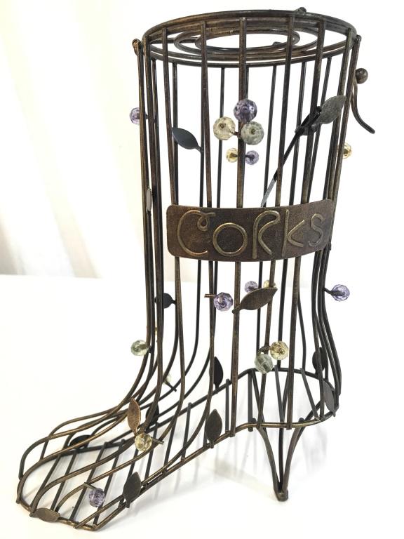 Heeled Boot Shaped Metal Cork Holder: Piece is metal. Front of piece reads CORKS. Piece is gold toned with leaf detail. Piece is in the shape of a heeled boot. Piec has lid. Measures approx 11 inches tall 8 inches wide, 4.5 inches deep. c