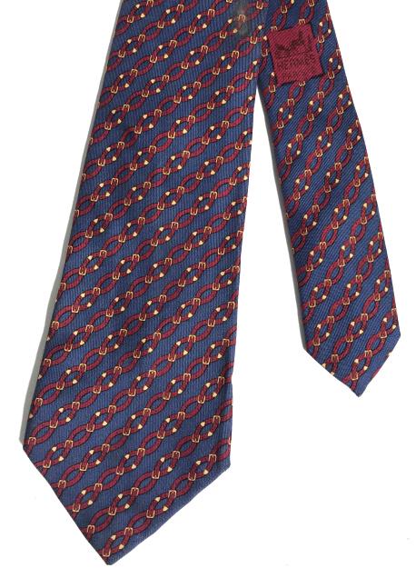 HERMÉS PARIS Silk Men’s Necktie: Hermés Paris necktie, the tie is 100% silk. Pattern covering the tie resembles series of belts being strapped together. The tie is colored in blue, red, and gold tones, the tie has a matching blue li