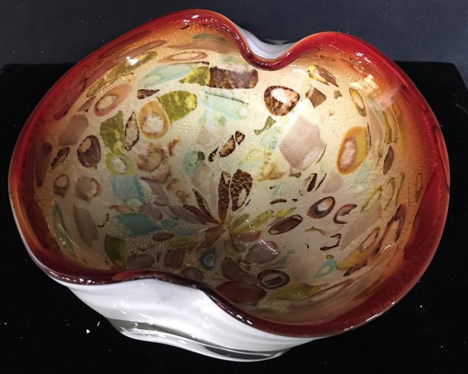 Mid Century Red Rim Art Glass Bowl: Iridescent Gold Flakes shine through the mosaic style pattern. Colored with aqua, yellow, browns and 1/2 in. brilliant red rim with pressed in sides. Measures 9 1/4 x 8 1/4 in. Ht 3 in. Artisanal Glas