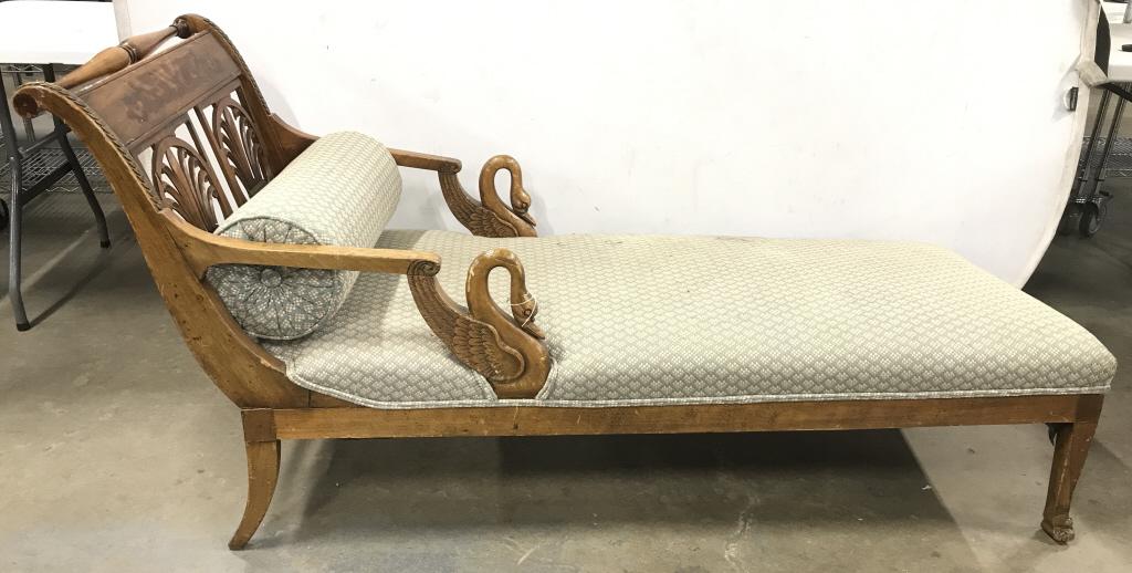 Vintage Carved Wooden Chaise Lounge: Chaise lounge is vintage possibly antique. Piece has carved Wooden swan detail at ends of arms. Piece is upholstered, includes cylindrical shaped pillow. Contains gold toned brass leaf detail. Backres
