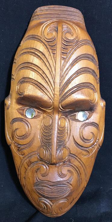Hand Carved Perata New Zealand Wooden Mask: Hand carved wooden mask, with abalone eyes. The mask features intricate carvings made to resemble the facial tattoos of indigenous peoples. The eyes are inlaid abalone Shell fragments. The piece measu