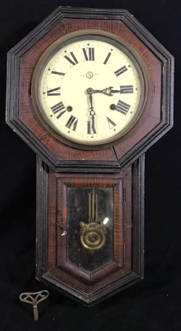 Antique SEIKOSHA Wooden Wall Clock: Antique SEIKOSHA Wall Clock. The piece is crafted from wood. The piece includes the Clock crank key and weight. The weight is brass and is decorated with brass leaves. The piece measures approx 21.6 i
