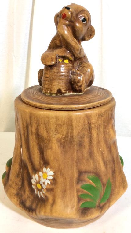 Vintage Ceramic Bear Cub Cookie Jar: Vintage ceramic cookie jar. The piece depicts a bear cub eating honey from a bee hive atop a tree stump. The piece is hand painted. The piece measures approx 14.6 inches H and 9 inches in diameter. Th