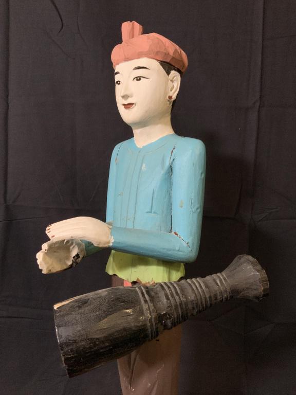Asian Hand Carved Wooden Figural Sculpture: Asian Hand Carved And Painted Wooden Figural Sculpture Depicting a figure standing playing a drum, some chips and cracks in areas, measures approximately 23 inches tall x 6.5 inches wide x 8 inches de