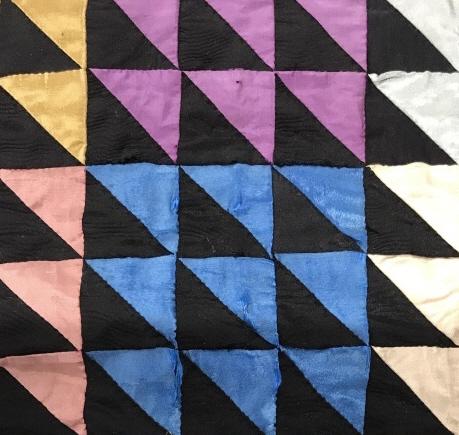 Antique Hand Stitched Quilt: Triangle Half Square Pattern bunched by color blocks with wide brown edge and black velvet/ plush border. Backing is a burgundy sateen like fabric, diamond design sandwich quilt pattern throughout. Fa