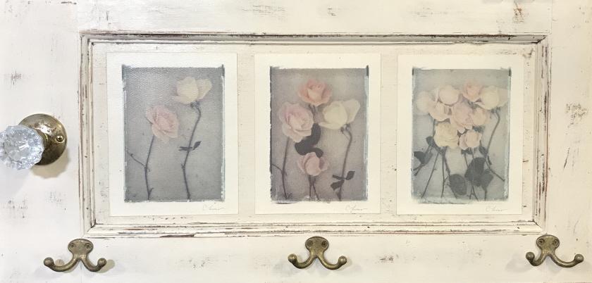 ANTIQUE REFLECTIONS Door Coat Rack With Rose Motif: Repurposed Door Coat Rack With Rose Motif, signed prints of pastel colored roses, signatures possibly in print, three brass tone metal coat hooks and one decorative glass doorknob, label on reverse re