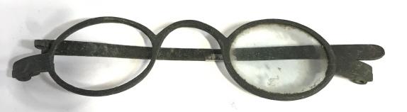 Antique Spectacles , c. Late 1800s, Victorian: Antique eyeglasses, Ben Franklin Style. 1 1/8 in. x 7/8 in. Oval lens, oval Curved nose bridge, One lens, one temple. Glasses 4 1/8 in. Long. Discoloration to metal due to age and exposure. Antiques, 