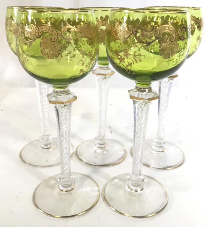 Set 5 Green Toned Bohemian Glass Stemware: Lot includes 5 glasses. Each glass is green toned with ornate gold toned detail. Each measures approx 7.5 inches tall 2.75 inches wide. Stemware, beverage glasses, bohemian glass, wine glasses, cordia