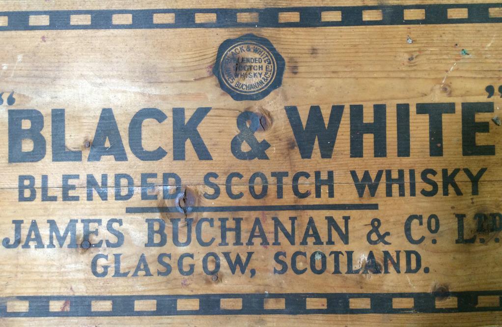Vintage BLACK & WHITE Whiskey Wooden Sign: This is a vintage wooden sign for BLACK & WHITE Whiskey from JAMES BUCHANAN & CO of Glasgow, Scotland. The piece measures approx 8.12 inches H and 17 inches W. The piece shows signs of wear consistent