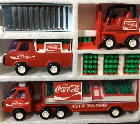 BUDDY L COCA COLA Collectible Delivery Truck Set: This is a set of vintage collectible delivery trucks from BUDDY L. The pieces each resemble COCA COLA delivery trucks, each truck as well as the loading ramp are crafted from metal. The largest piece