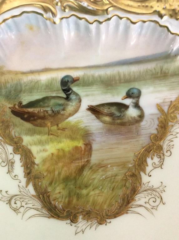 Set 12 Souvenir T&V Limoges, Birds in Marsh Motif: Heavily Gilt scalloped rim in relief, fine lines of scrolls and swirls accenting painted water fowl birds in a marsh. Each plate has a different bird- mallard Ducks, pheasant, pigeon, partridge, etc. 