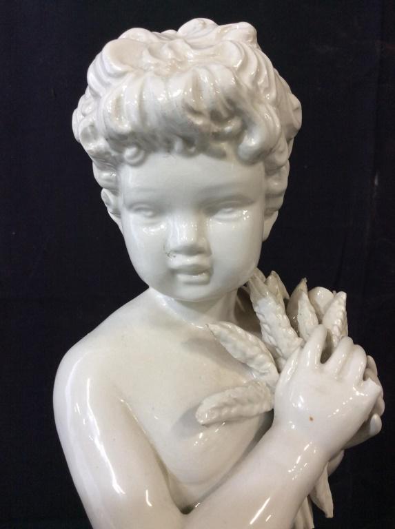 Blanc de Chine Ltd Edition cherub Statue, Italy: Numbered 35/200 with letter ‘B’ and ‘Italy’ handwritten on underside sticker label. Glazed porcelain Cherub boy holding wheat grain in hands, draped in half Roman toga.19 in tall, 6 in wide. V