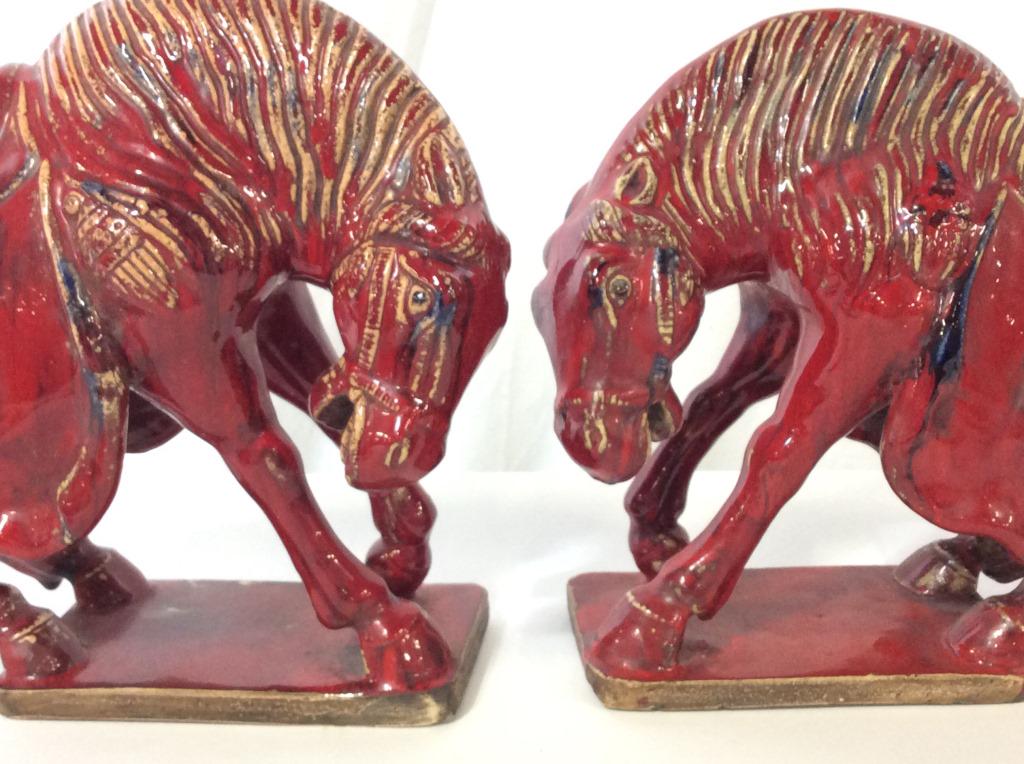 Pair Red Glazed Asian Horse Sculptures: Vintage red glazed Asian Warrior Horse Statures with navy and peach glazed patina accents. On Terra Cotta Bases. Horses decorated with ceremonial garb, glazed and embossed. Hand formed & Painted. Size