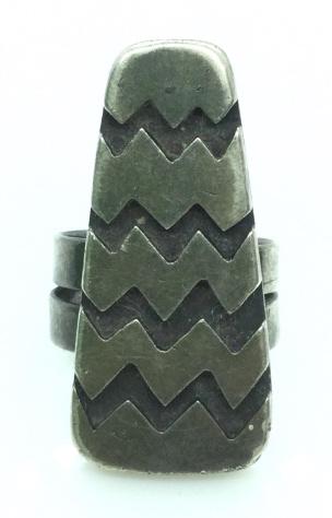 Sterling silver Cocktail ring: Dark toned metal, raised 'zig zag' line design, band is warped, fits an approx size 6. No hallmark noted. Face measures approx approx 3/4 in by 1 1/2 in. 12.1 dwt. Some surface wear. Sterling silver, 