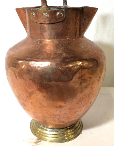 Primitive Antique Copper & Brass Water Jug: Pitted & Hammered copper jug used to scoop water from well. Double sided spouts. Solid copper handle , possibly copper plated brass handle. Brass base. App 16.5 in ht, 9 in width, has dent. Minor oxid