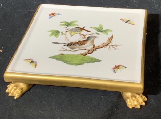 Hand painted HEREND Porcelain Trivet: Raised HEREND porcelain ceramic trivet with feet and painted. Border and feet are gold toned. Measures approx 7 by 7 inches. Underside reads 0163 Herend Hungary hand painted 6410,20 21. Trivet, displa