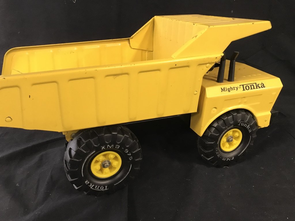 Vintage MIGHY TONKA Dump Truck Toy c.1970s: Bright yellow toy dump truck, MIGHTY TONKA sticker labels on sides and front. Pressed steel. Very cool Tonka XMB-975 Wheels. Normal vintage nicks, dings, no rust. L 19 in, W 8 in., Ht 10 in. Collectib