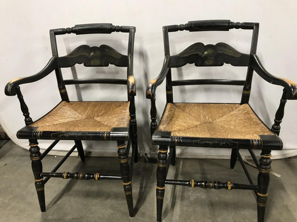 Pair Vintage Wood & Rush Armchairs: This is a pair of wooden armchairs. The pieces have rush seating and have been colored a black tone. The central cross rail of each chair is decorated with a painting of an Eagle. Gold detailing is pr