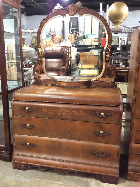 Art Deco Waterfall Mirrored Topped Dresser: Vintage Walnut Toned Wooden Art Deco Waterfall Dresser With Mirror Top, circular bakelite accents under brass toned metal drawer pulls, three lower dovetailed drawers, carved and inlaid Scroll & Leaf 