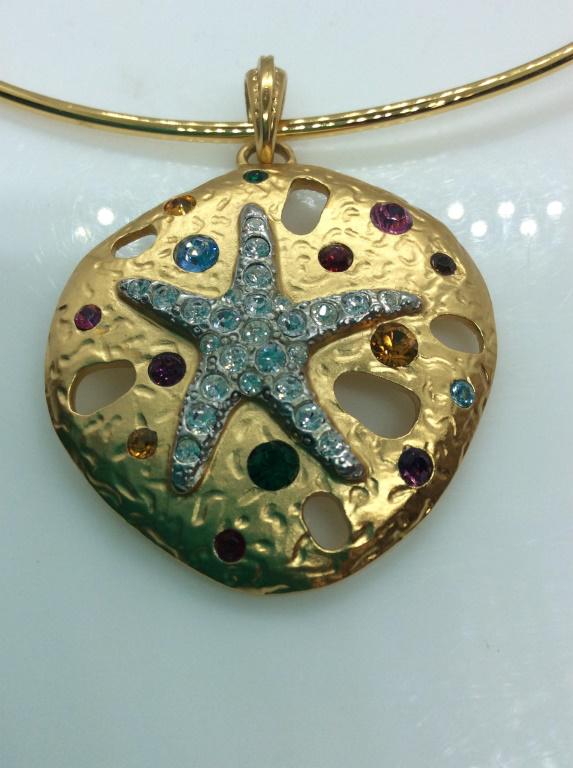 Kenneth Jay Lane Rhinestone Sea Shell Necklace: Wire collar necklace in yellow gold tone metal with pendant, center clear rhinestone starfish, colored rhinestone rounds, pendant 1 3/4 in. diameter. Collar 5.5 in diameter, Signed Joan Rivers. Signed