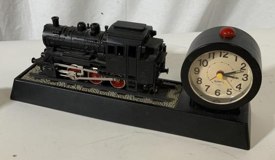 Vintage Model Train Tabletop Clock: Vintage black tone model train clock. Constructed from plastic. Measures approx 13 inches long and 6 inches tall. Inside of clock reads Quartz Taiwan. Red alarm clock button. Holes at end in front of 