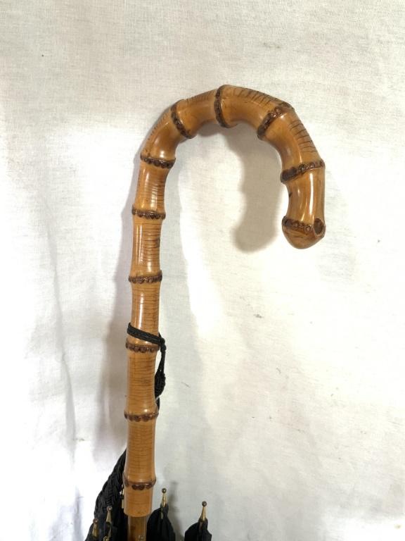 Vintage UNCLE SAMS Umbrella, England: This piece is a vintage umbrella. The wooden handle is hand carved to resemble bamboo, and is adorned with a black, braid tassel. The tip of the umbrella is also crafted from wood and capped with bras
