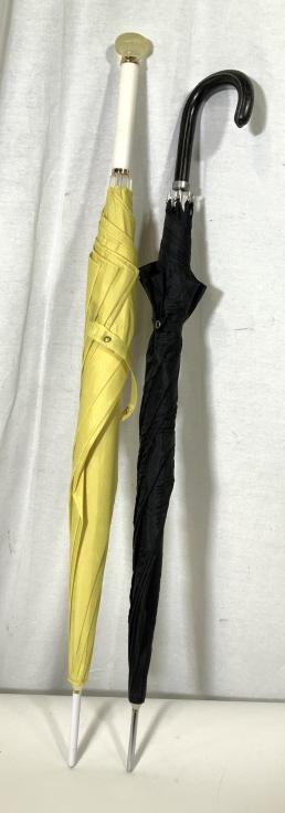 Lot 2 Vintage Umbrellas: This is a lot of 2 vintage umbrellas. One of the handles pears to be made of a composite material, the other appears to be leather. The canopies of both umbrellas appear to be crafted from nylon. The 