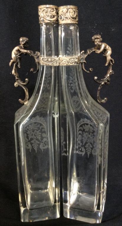 Pair Etched Glass Putti Handle Cruets: Vintage Oil & Vinegar Cruet Glass Bottles adorned with scroll & Putti Handles. Substantial glass thickness, metal possibly silver plated, no stoppers, 11 in ht, Glass width 2 in, handle measures 3 x2 