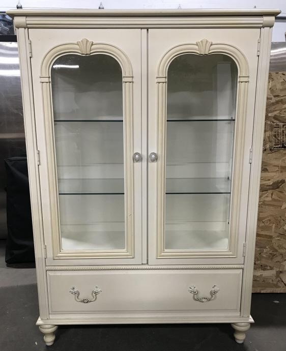 STANLEY FURNITURE Carved Wooden Display Case: Display case is marked STANLEY FURNITURE on interior of drawer. Piece has windowed doors. Contains 2 glass shelves. Door handles are possibly Lucite. Piece has one drawer with ornate metal handles. Pi