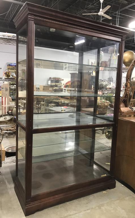 KHALID HOWARD MILLER Lighted Curio Cabinet: Tag on lower area reads HOWARD MILLER. Curio Cabinet is wooden. Piece includes 4 glass shelves. Piece has intricately carved wooden detail. Piece measures approximately 80 inches tall 49 inches wide 2