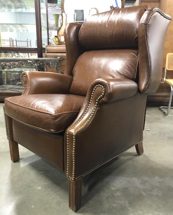 Vintage Brown Toned Leather Reclining Armchair: Armchair is brown toned and appears to be genuine leather. Piece has gold toned nailhead detail. Armchair reclines. Piece has winged backrest. Recliner measures approximately 43 inches tall 34 inches 