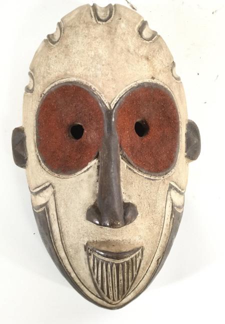 African White Face Igbo Ceremonial Mask, Nigeria: Tribal Mask from the Igbo located in current Nigeria, West Africa. carved dark wood, sections painted with white kaolin, large open eyes with red plant textured paste. Measures 14 in.long, 9.5 in. wid