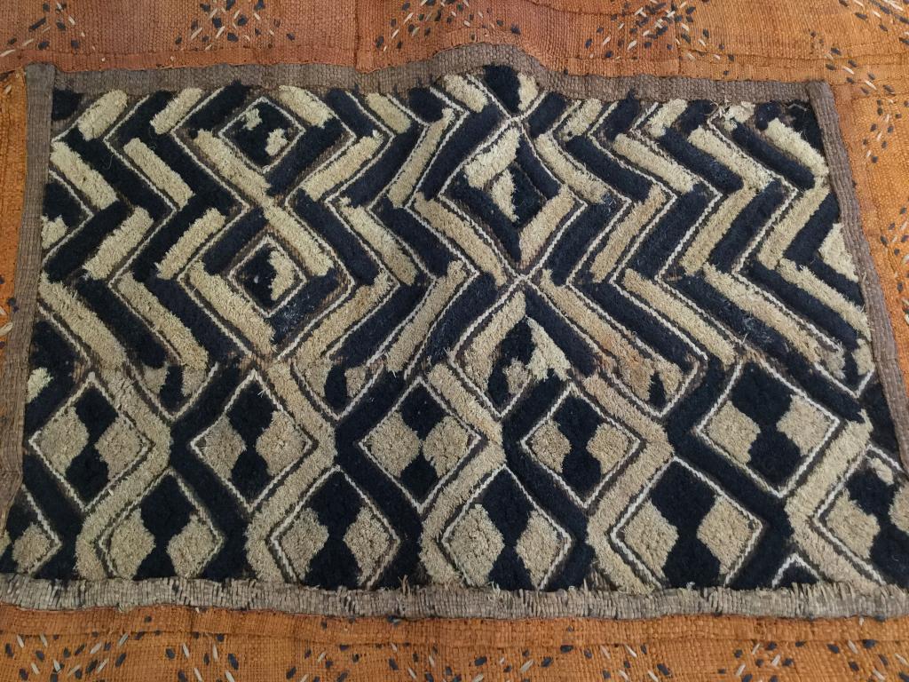 Kuba African Woven Raffia Tapestry, Congo: Handmade raffia Tapestry/ furniture cover/ table runner/ wall hanging. Center shaved Raffia in chevron & diamond pattern. Raffia Cross Cross stitching throughout. Dyed colors black, orange, & natural.