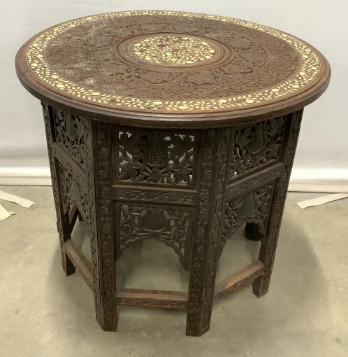 Antique Intricately Carved Side Table, India: This is an antique wood side table, the piece was crafted in India, and appears to be rosewood. The table as well as it’s folding base are intricately carved and detailed. The carvings depicts flora