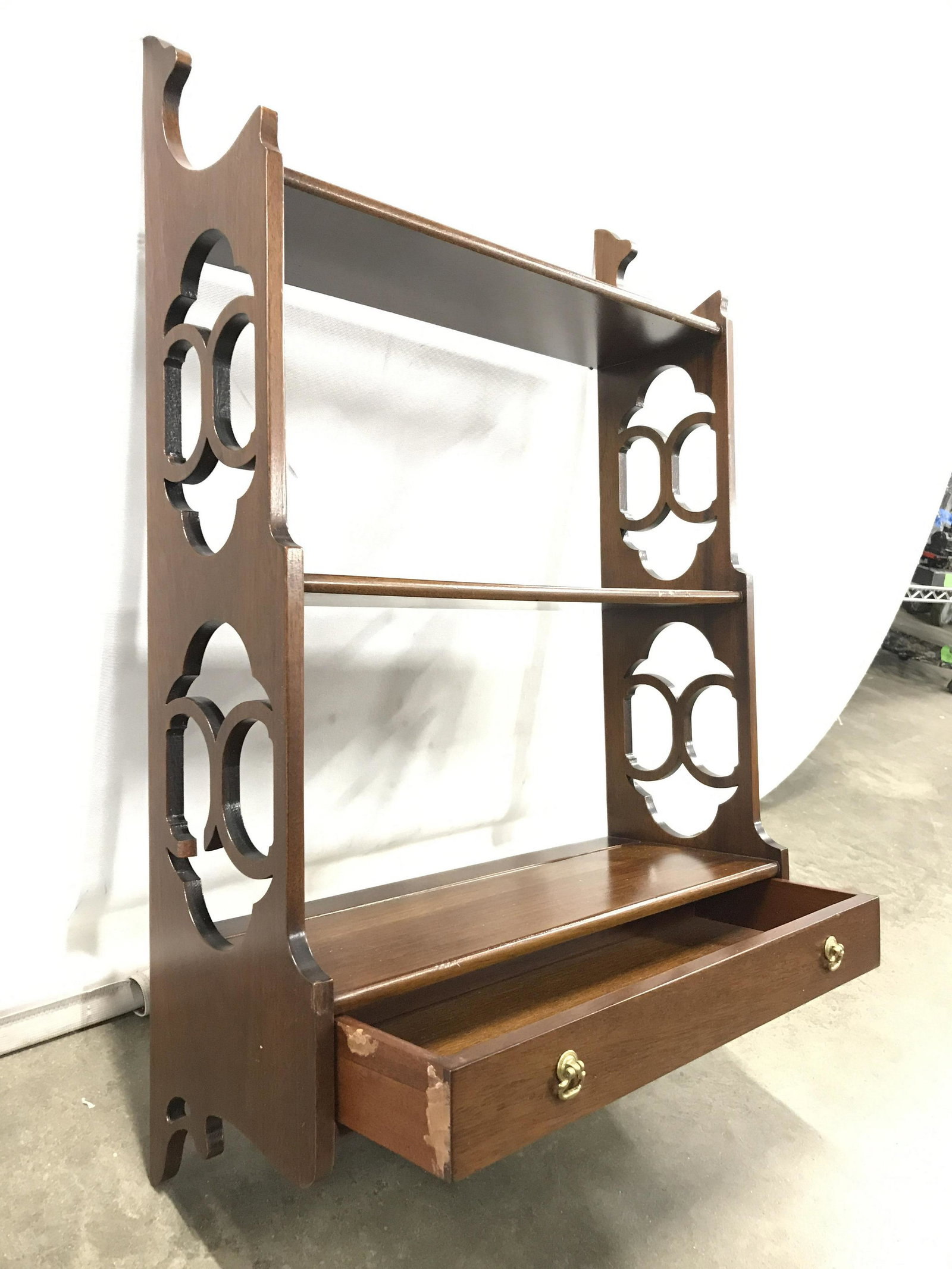 Carved Wooden Wall Shelf W Drawer: Wall shelf is wooden. Piece has light brown tone. Piece has 1 drawer with petite gold toned handles. Piece measures approximately 26.5 inches tall 17 inches wide 7 inches deep. shelf, display shelf, h