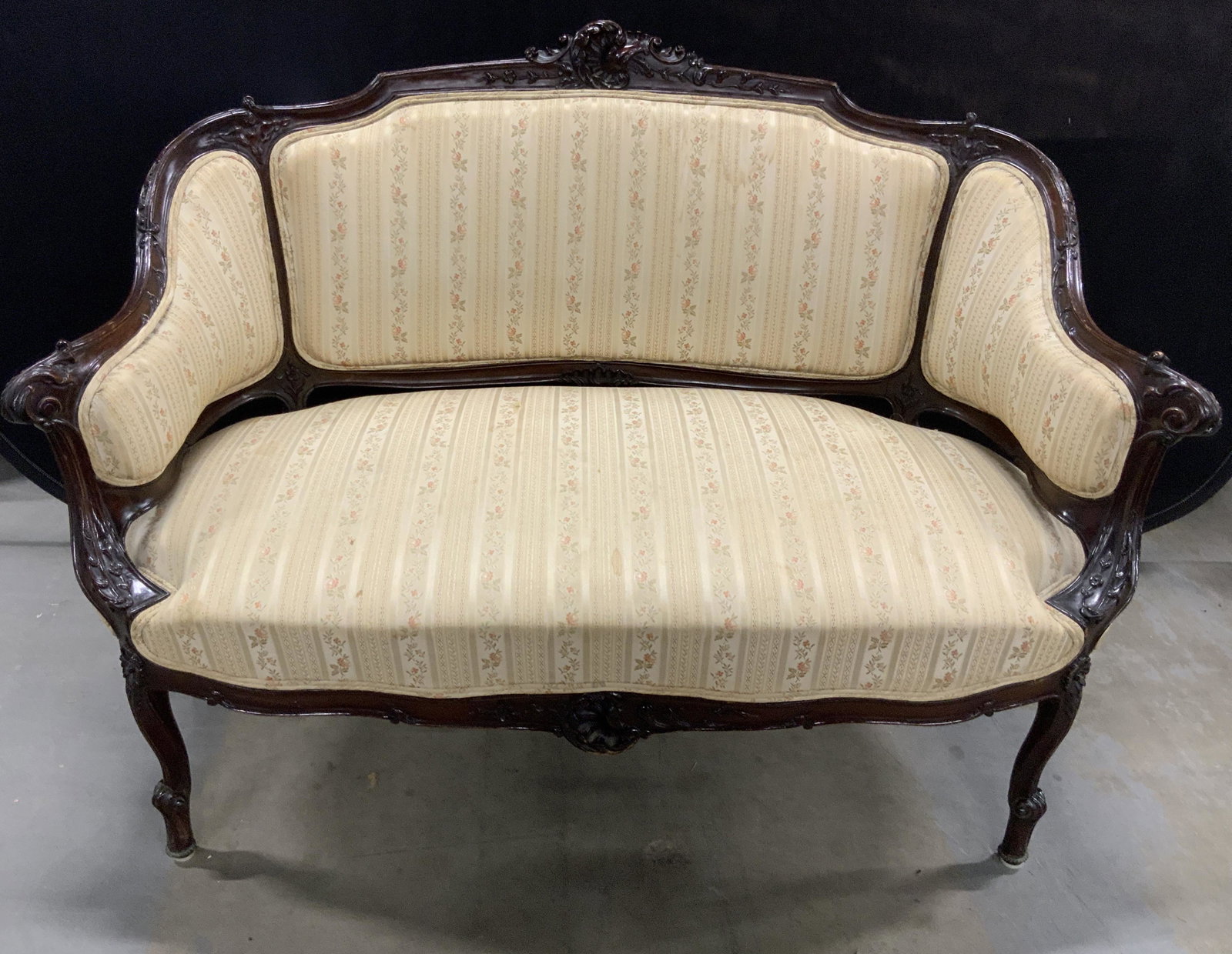 Antique French Carved Wood Upholstered Loveseat: This is an antique, upholstered, French sofa/loveseat. The piece is upholstered and double welted, the frame is hand carved, the apex of the piece’s back is adorned with an intricately carved floral