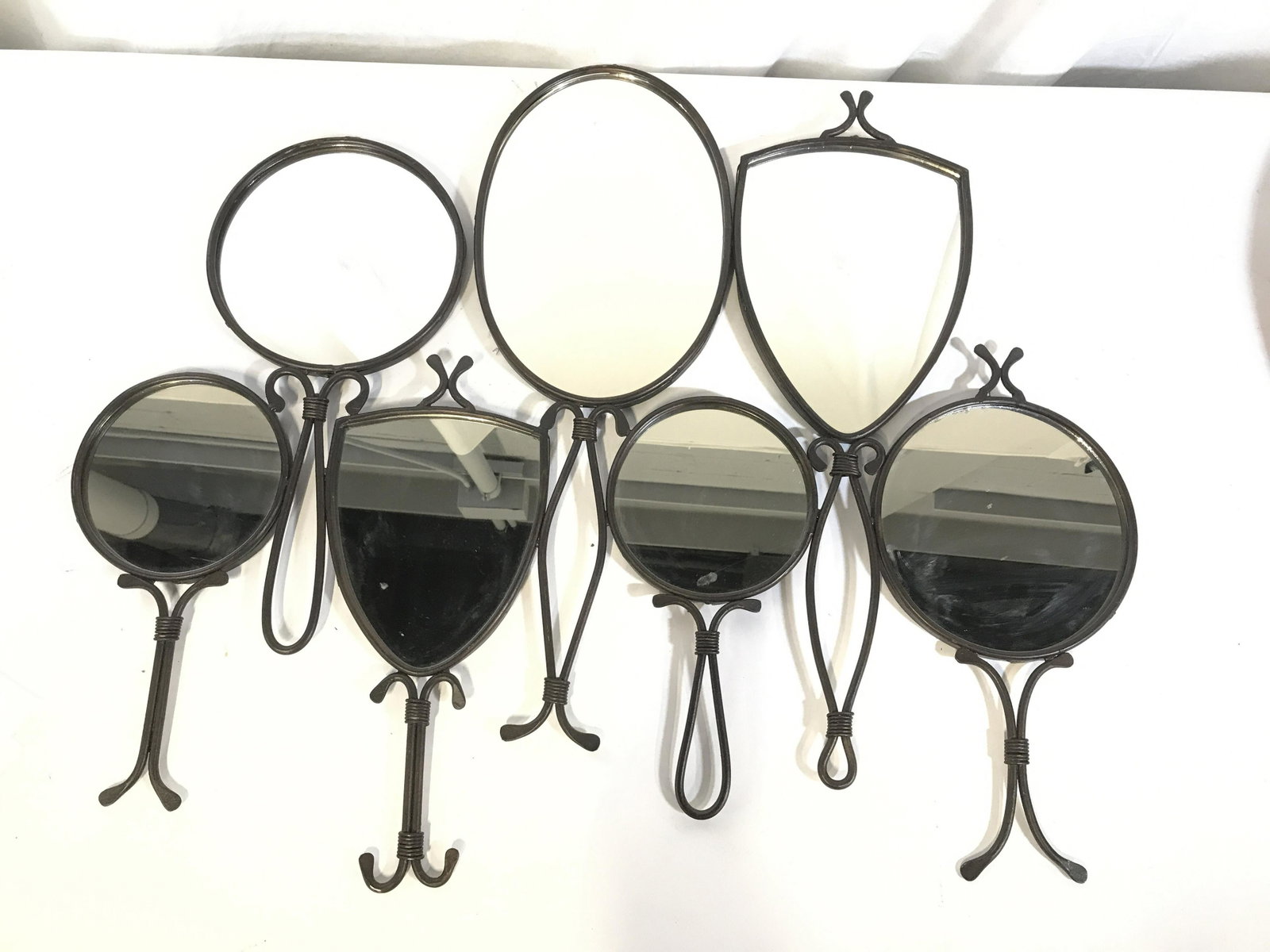 BronzeToned Multi Hand Mirror Wall Collage: Bohemian chic wall Decor. 7 hand-held style and dresser top style mirrors fused in one large collage. Measures 31 in wide, 25 in ht. Metal is an antique bronze patina. One mirror with a couple of scra