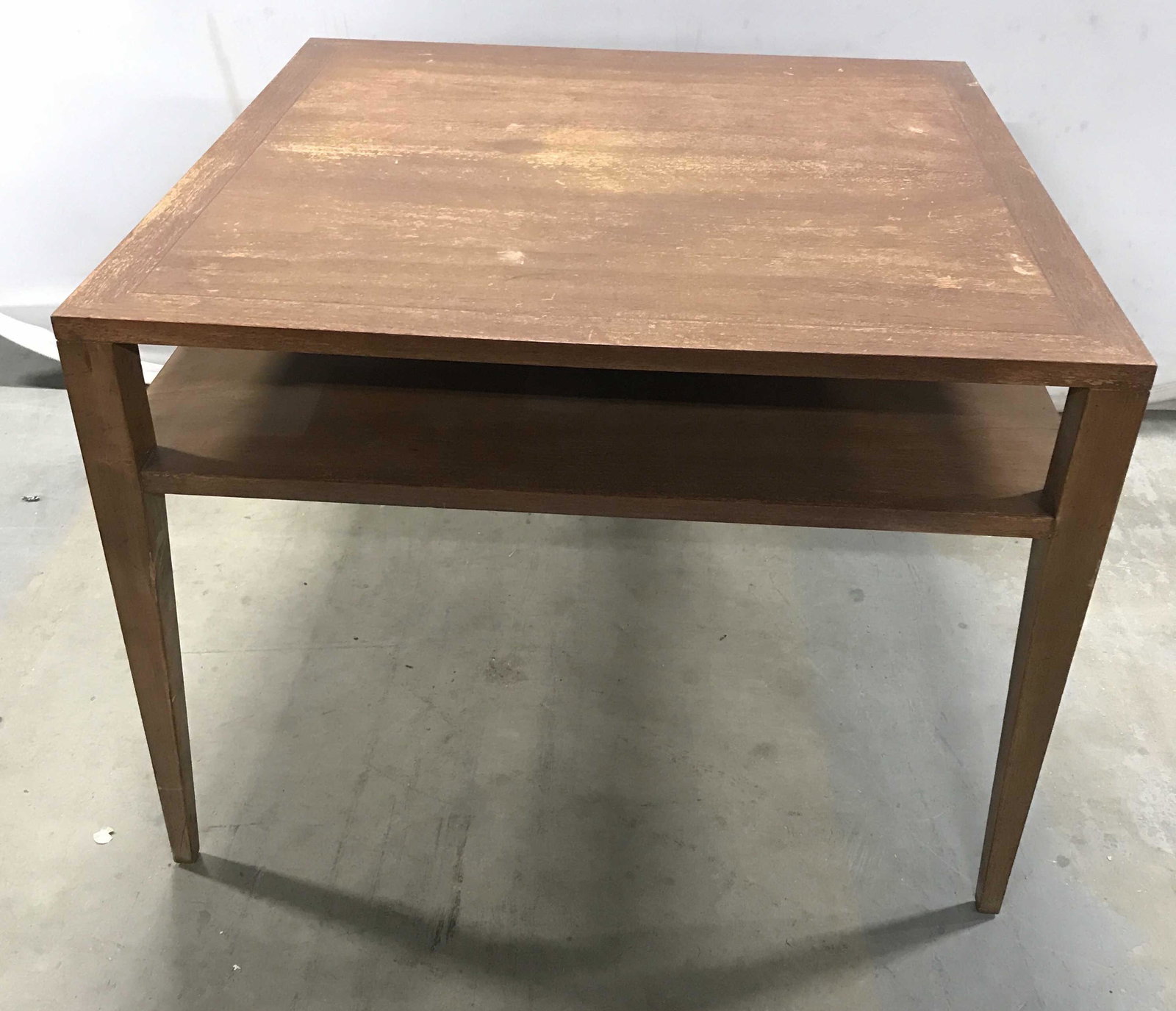 Vintage MCM Wooden Coffee Table: This is a vintage coffee table, the piece is crafted from wood. There is a shelf space available for storage. The table is walnut toned, and measures approx 22 inches H, 30 inches W, and 30 inches dee