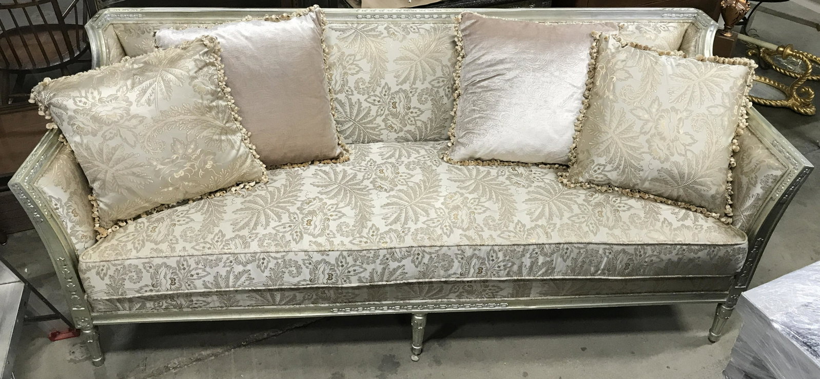 Lot 4 YARAGHI Gold Toned Ornate Sofa W Pillows: Tag underneath cushion reads YARAGHI LLC Lot includes 1 sofa and 4 pillows. Sofa is gold toned with Upholstered floral, leaf and vine detail. Sofa frame appears to be wooden, Contains carved Detail. P