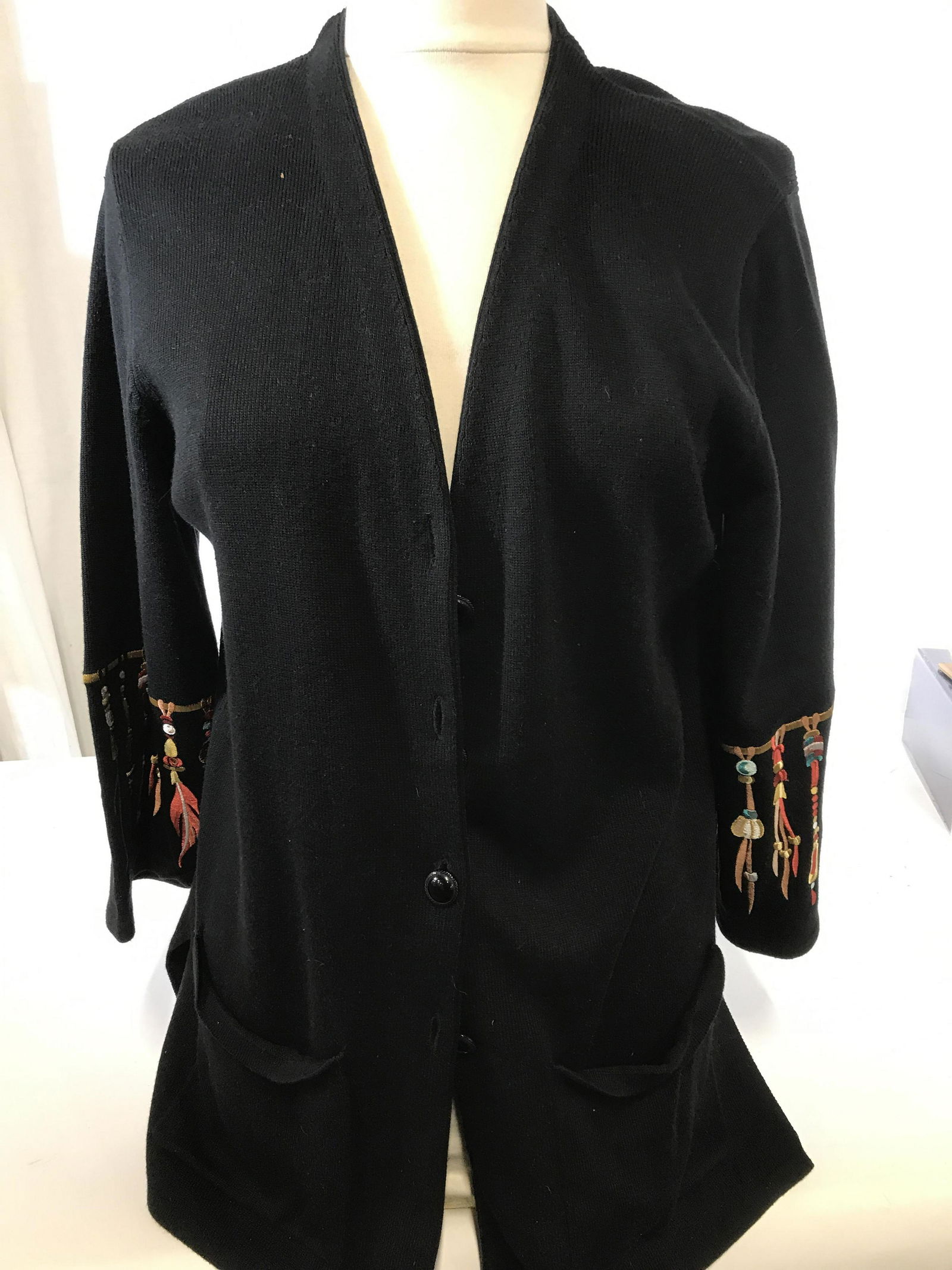 BOB MACKIE ‘Wearable Art’ Button Down Sweater: Black button down 3/4 sleeve cotton sweater. Embroidered Native American Feather Tassel Design on sleeves and dream catcher on backside. Large hand pockets, 4 front buttons ( xtra button sewn on inter