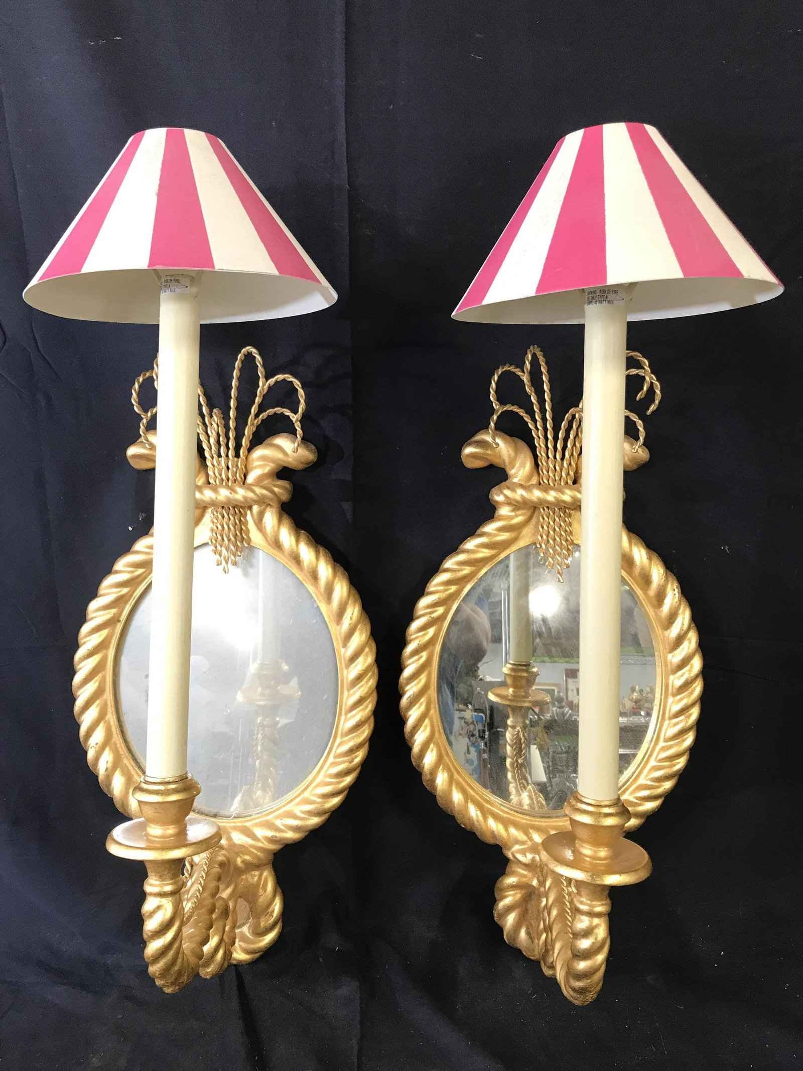 Pair Ornate Gold Leaf Wall Sconces W Mirrors: Lot includes 2 sconces. Each are gold toned with oval shaped mirror. Piece has rope twist style frame. Pieces appear to be gold leafed. Sconces include shades. Each measures approx 32 inches tall 13 i