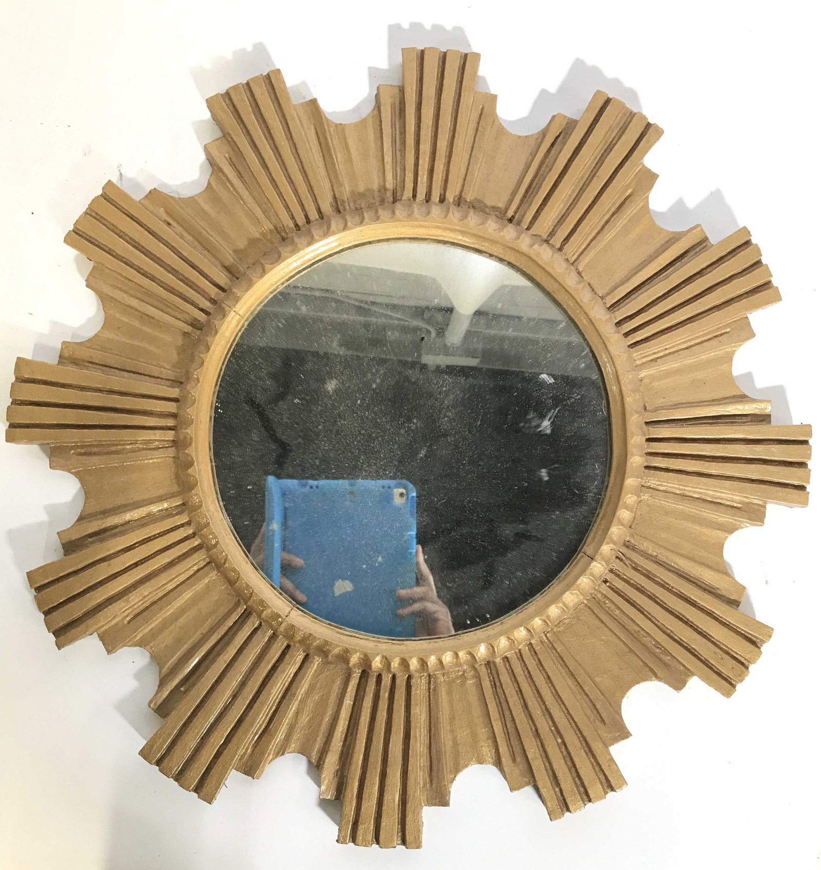 Gold Toned Frame Sunburst Wall Mirror: Mirror frame is gold toned. Frame appears to be wooden. Frame appears to possibly be gold leafed. Piece measures approximately 23.5 inches wide and tall. Mirrored surface is circular. Sunburst mirror,